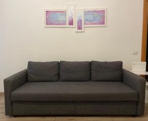 a couch in a living room with three pictures on the wall at EasyRome - Appartamento a Roma San Paolo in Rome