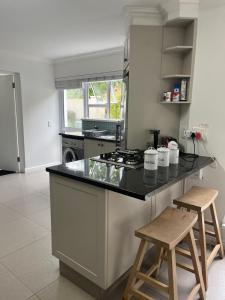 a kitchen with a stove and two stools in it at Stableford Beach House Plett in Plettenberg Bay