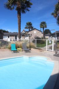 - une piscine bleue avec 2 chaises et des palmiers dans l'établissement Hôtel les 13 Assiettes, à Le Val-Saint-Père