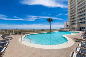 a swimming pool with chairs and a palm tree at Lighthouse 714 in Gulf Shores