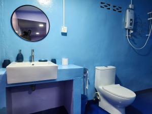 Baño azul con lavabo blanco y espejo en Gecko Guesthouse, en Pantai Cenang