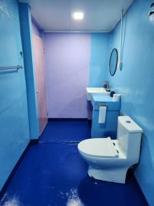 a blue bathroom with a toilet and two sinks at Gecko Guesthouse in Pantai Cenang