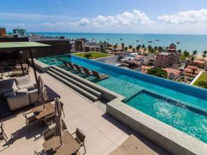 una piscina en la parte superior de un edificio con el océano en HOLANDAS PRIME TAMBAU Flat, en João Pessoa