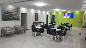a dining room with tables and chairs and a green wall at pousada costa do meio in Saquarema