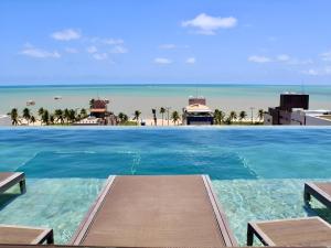 a swimming pool with a view of the ocean at HOLANDAS PRIME TAMBAU Flat in João Pessoa