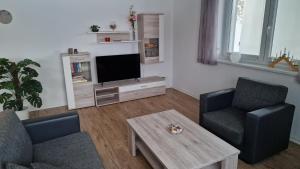 a living room with a tv and two chairs and a coffee table at FeWo "Am Auwald" in Leipzig