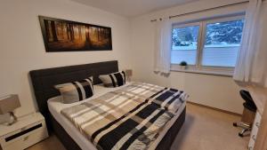 a bedroom with a bed with a comforter and two windows at FeWo "Am Auwald" in Leipzig