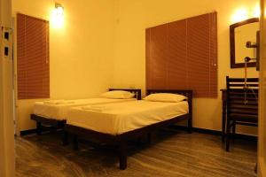 two twin beds in a room with two windows at Janatha Homestay in Cochin