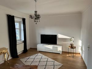 - un salon blanc avec une télévision et un lustre dans l'établissement Mühlbach´s, à Kaufbeuren