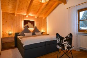 ein Schlafzimmer mit einem Bett und einem Stuhl in der Unterkunft Bodenmaiser Herz-Hoamad Ferienwohnung Bierl in Bodenmais