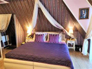 フランチシュコヴィ・ラーズニェにあるRezidence Zámeček - Boutique Hotelのベッドルーム(紫色の枕が付いた天蓋付きベッド付)