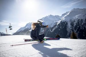 a woman is sitting on a snow covered ski slope at Quality Hosts Arlberg - AFOCH FEI - das Landhaus in Sankt Anton am Arlberg