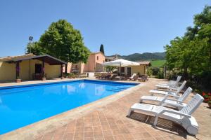 une piscine avec des chaises longues et une maison dans l'établissement Villa Santa Maria Deruta, à Deruta