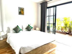 a white bedroom with a bed and a large window at Baan Purada in Ko Lanta
