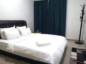 a bedroom with a large white bed with blue curtains at iG Hotel in Alor Setar
