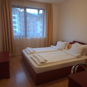 1 dormitorio con 1 cama con sábanas blancas y ventana en Todorini Kuli Apartments, en Bansko