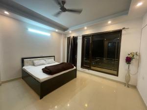 sypialnia z łóżkiem i dużym oknem w obiekcie Own Stay w Nowym Delhi