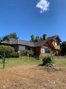 a log cabin house with a porch and a yard at La Soñada casa de montaña in San Martín de los Andes
