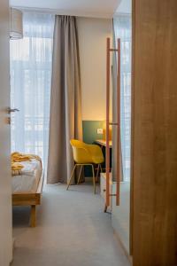 a bedroom with a bed and a desk with a yellow chair at Willa Zalesie in Krynica Zdrój