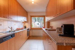 a kitchen with wooden cabinets and a large window at Chalet Casa Acla Laax in Laax