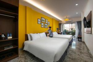 a woman standing between two beds in a hotel room at Hanoi La Cascada House & Travel in Hanoi