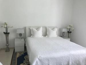 um quarto com uma cama branca com lençóis e almofadas brancos em Ferienhaus am Lünner See em Lünne