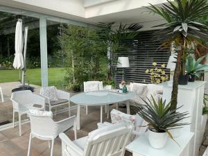 a patio with white chairs and a table and a table and chairs at Ferienhaus am Lünner See in Lünne