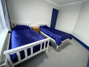 2 Betten in einem Schlafzimmer mit blauer Bettwäsche in der Unterkunft Harewood Lodge - Single and Double Rooms Self Serve Apartment in Kings Lynn