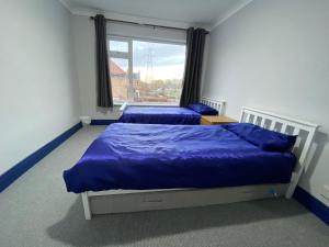 1 Schlafzimmer mit 2 Betten mit blauer Bettwäsche und einem Fenster in der Unterkunft Harewood Lodge - Single and Double Rooms Self Serve Apartment in Kings Lynn