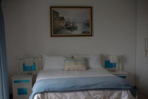 sypialnia z łóżkiem z obrazem na ścianie w obiekcie Pearl Oyster guesthouse w mieście St Francis Bay