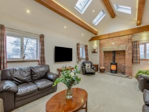a living room with a leather couch and a fireplace at Clarion Lodge Cottage Ilkley in Menston