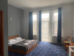 a bedroom with a bed with blue carpet and windows at Vila Themis in Călimăneşti