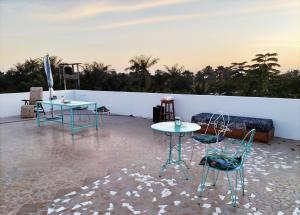 - deux tables et des chaises au-dessus d'une terrasse dans l'établissement Maison d'hôtes Keur Racine, à Cap Skirring