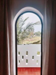 an arched window in a room with a palm tree at Maison d'hôtes Keur Racine in Cap Skirring