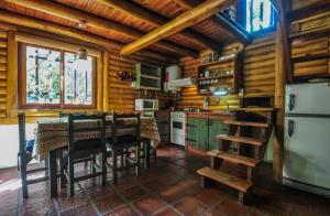 cocina con paredes de madera, mesa y sillas en Cabañas Huincul en Villa Gesell