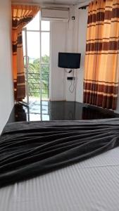 a bedroom with a bed with a television and a window at Air Vision 98 in Katunayaka