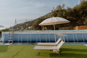 una silla y una sombrilla junto a la piscina en Sea Home above Sori village, en Sori
