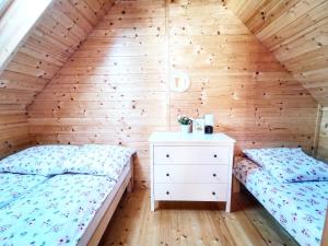 two beds in a attic bedroom with wooden walls at Czarne Domki Chłopy in Chłopy
