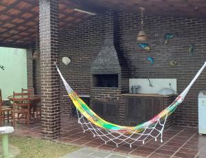 a hammock hanging in front of a brick fireplace at Casa Perto da Praia Caraguatatuba in Caraguatatuba