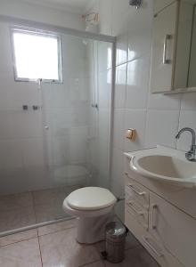 a white bathroom with a toilet and a sink at Casa Perto da Praia Caraguatatuba in Caraguatatuba +10 photos