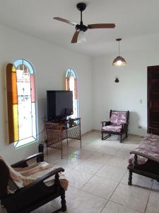 a living room with chairs and a flat screen tv at Casa Perto da Praia Caraguatatuba in Caraguatatuba