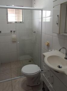 a white bathroom with a toilet and a sink at Casa Perto da Praia Caraguatatuba in Caraguatatuba
