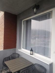 einen Balkon mit einem Holztisch und Stühlen sowie einem Fenster in der Unterkunft Delux Flat Straja-Lupeni in Lupeni