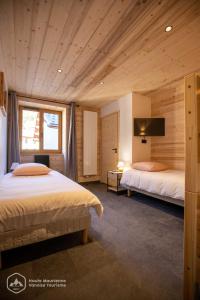 two beds in a room with wooden walls and ceilings at "Le Temps Suspendu" in Termignon