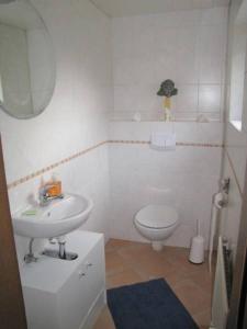 Baño blanco con lavabo y aseo en Smuk udsigt, en Gelting