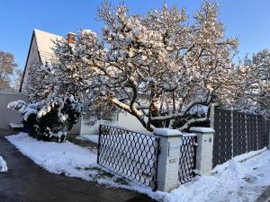 Ein schneebedeckter Baum neben einem Zaun in der Unterkunft Domizil Altötting in Altötting