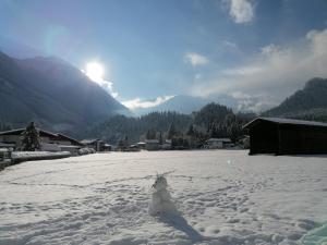 Un bonhomme de neige se tient debout dans un champ enneigé dans l'établissement Bergblick Apartment, à Wald im Pinzgau