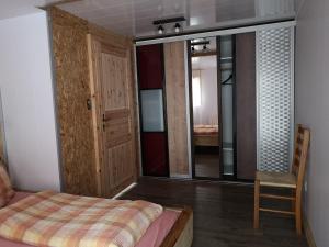 ein Schlafzimmer mit einem Bett, einem Stuhl und einem Spiegel in der Unterkunft Chez Martial in Hasliberg