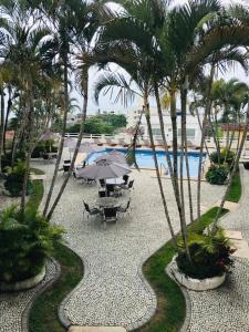 a patio with a table and umbrella next to a pool at Hotel Nova Guarapari in Guarapari