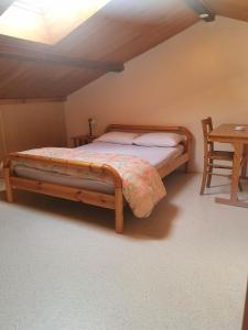a bedroom with a bed with a wooden frame and a table at Gite la famille SAVOYE in Chiroubles